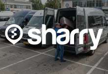 Sharry на фоні водія, який складає валізи в багажник мікроавтобусу