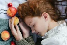 Serene image of a woman with closed eyes holding fruit. Captures tranquility and nature.