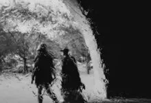 Abstract black and white photo of silhouettes seen through rain-covered glass, creating a textured effect.