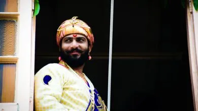 Smiling man in traditional attire looking through a window, embodying cultural heritage.