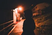 A captivating silhouette of a person walking through a dimly illuminated village at night.