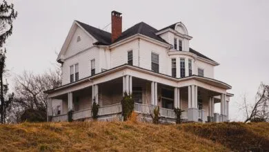 Beautiful historic white house with a wraparound porch set against autumn surroundings.