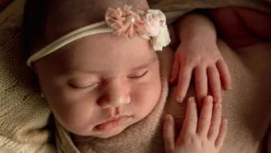 A serene image of a sleeping baby wearing a delicate floral headband, captured indoors.