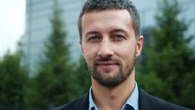 Portrait of a confident adult man with a beard in an outdoor setting.