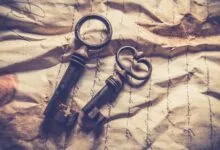 Vintage iron keys resting on crumpled, handwritten paper with a rustic texture.