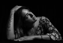 Elegant black and white portrait of a woman with floral tattoo, gazing thoughtfully.