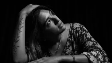Elegant black and white portrait of a woman with floral tattoo, gazing thoughtfully.