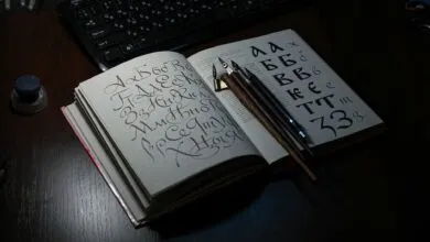 Open book showing Cyrillic calligraphy with quill pens on a desk, ideal for art and language themes.