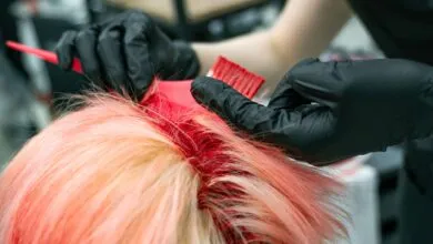 Close-up of vibrant hair coloring process with gloved hands applying dye.