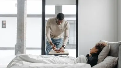 A man cares for his sick wife in bed, bringing her a cup of tea indoors.