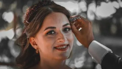Close-up of a smiling bride being adorned with jewelry, showcasing an intimate wedding moment.