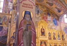Richly decorated Orthodox church interior showcasing intricate frescoes and religious icons.