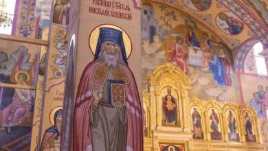 Richly decorated Orthodox church interior showcasing intricate frescoes and religious icons.