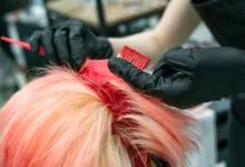 Close-up of vibrant hair coloring process with gloved hands applying dye.